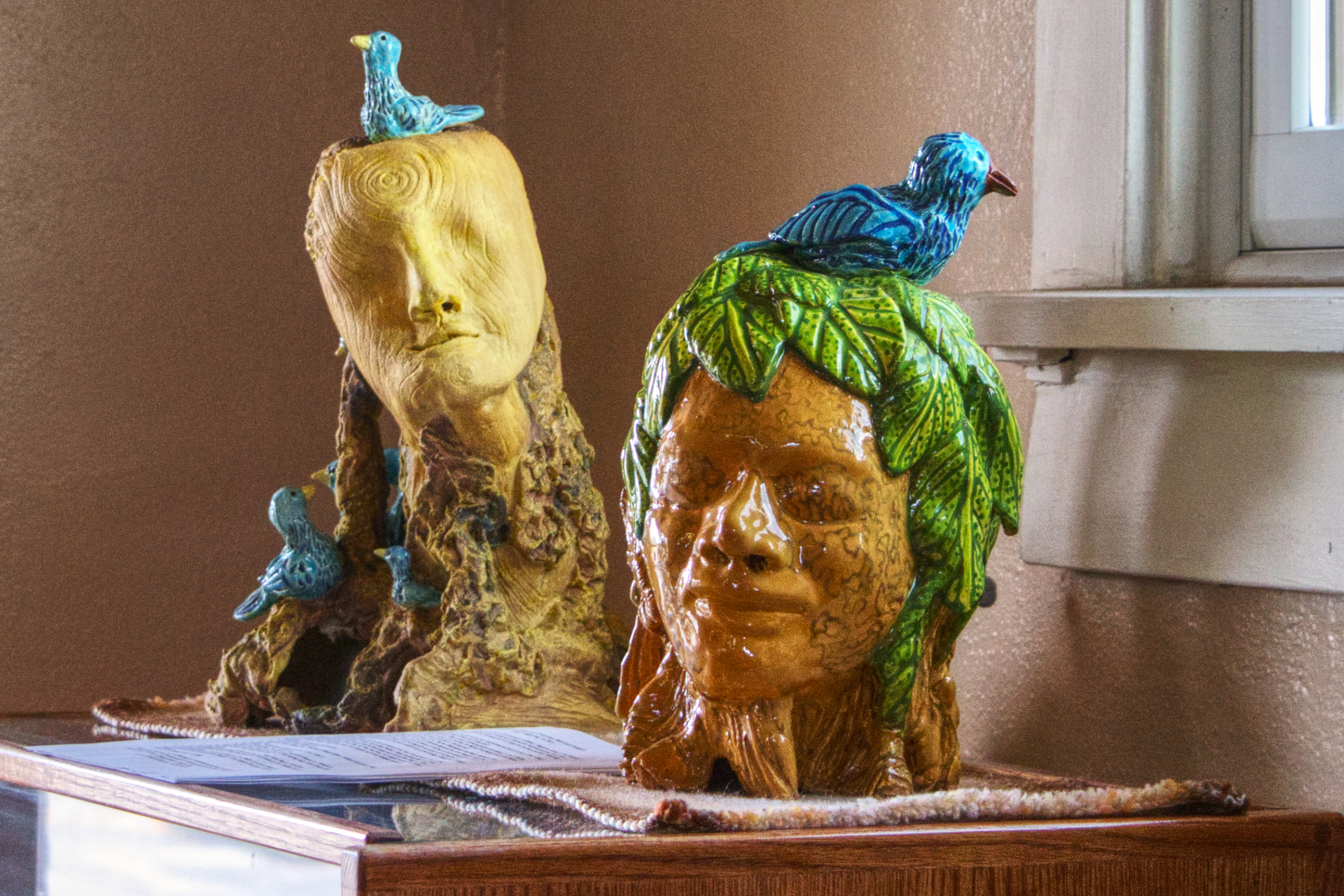 Two sculptures of heads with blue birds sitting on top of them