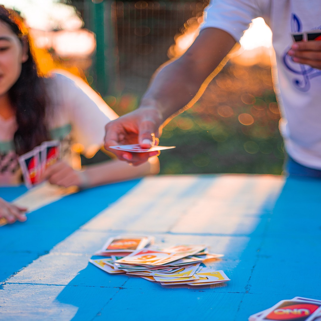 Two people playing UNO outside on a sunny day.