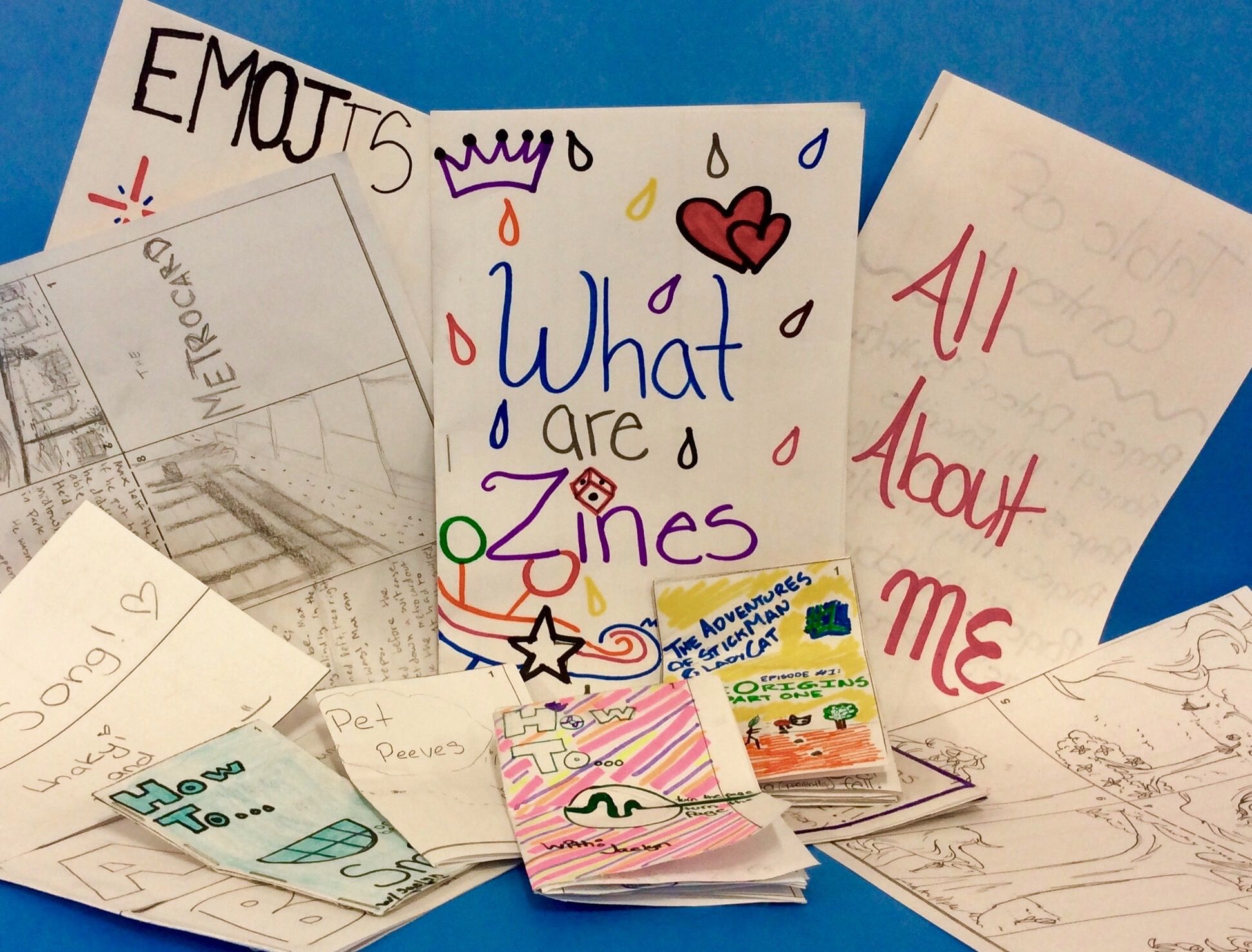 Multiple pieces of paper folded into zines with children's writing and illustrations on them