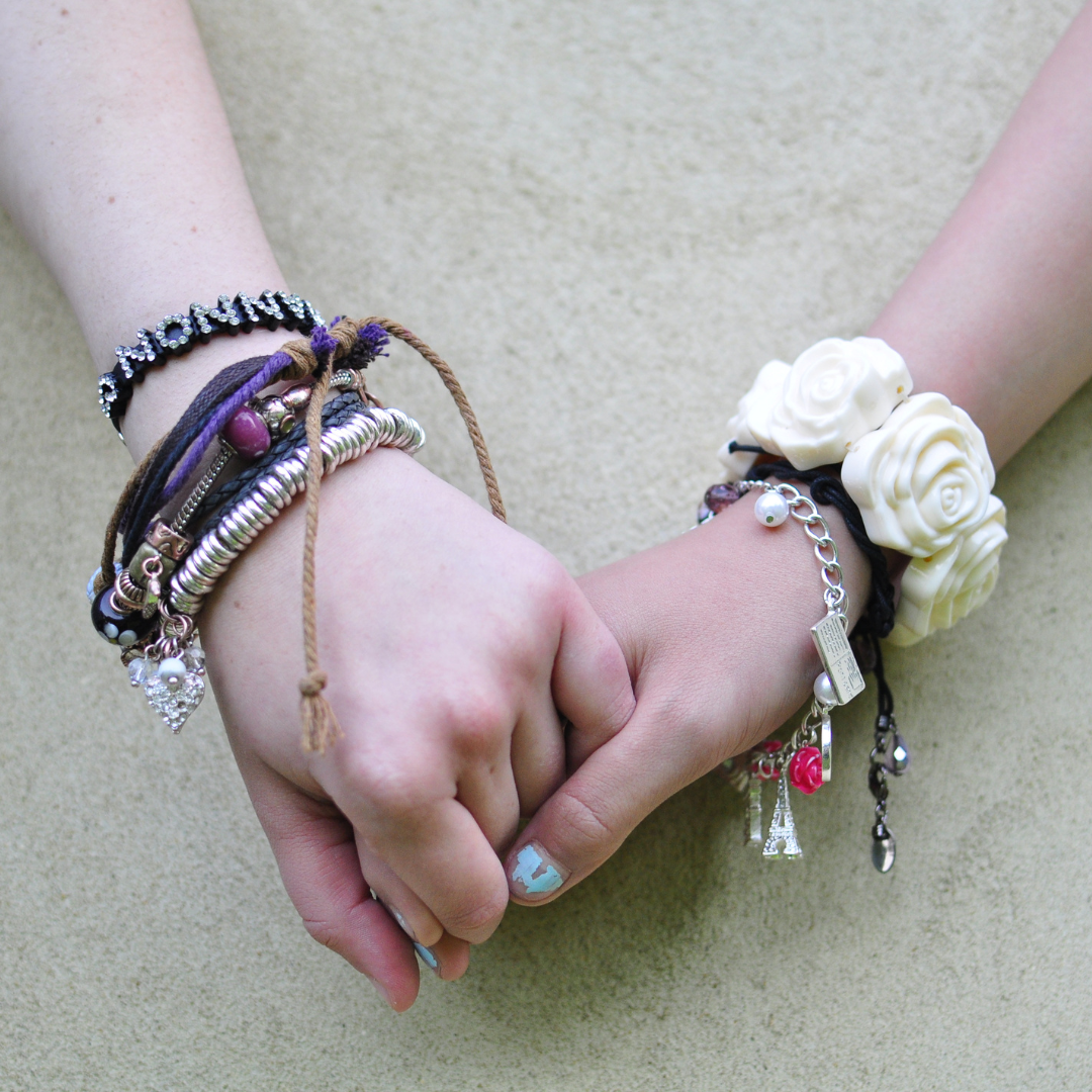 Two girls holding hands wearing bracelets