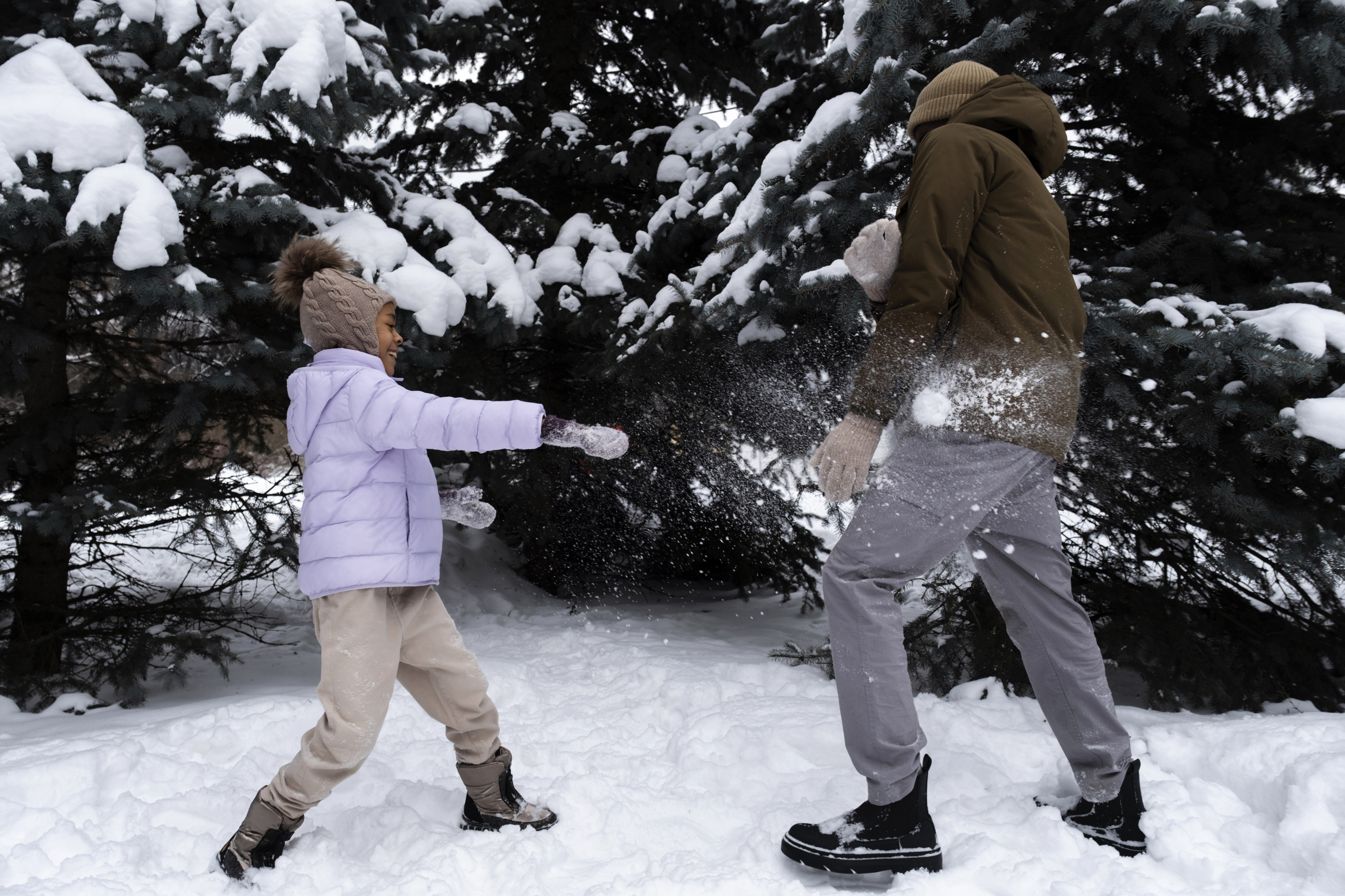 Young girl having a snowball fight with an adult