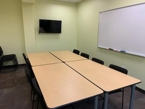 Key Lime Room with lime colored walls, and rectangular tables pushed together to create a central conference table; white board on wall