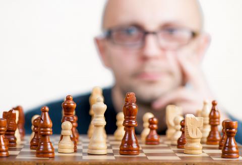 Man pondering his next move while studying a chess table and chess pieces
