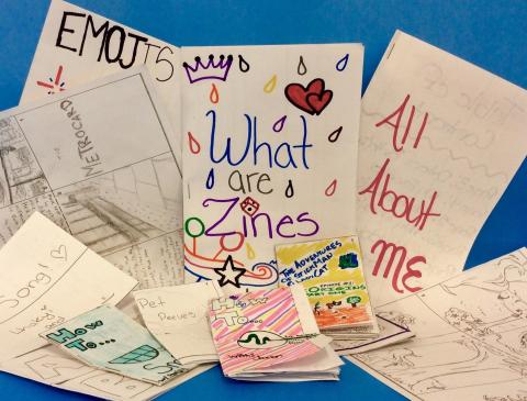 Multiple pieces of paper folded into zines with children's writing and illustrations on them