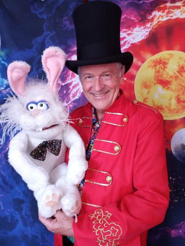 man in magicians costume holding a rabbit puppet