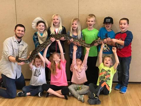 kids holding a large snake