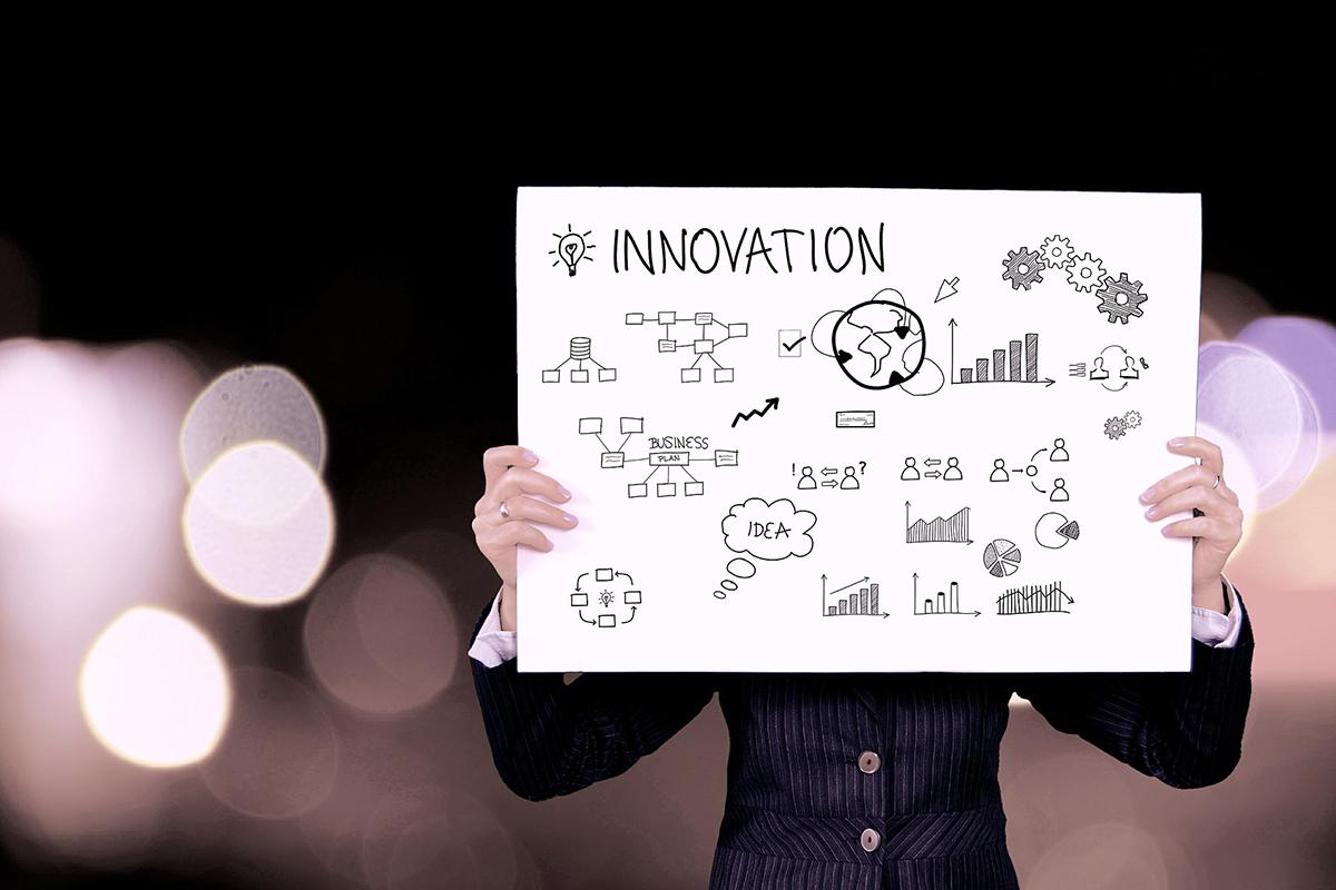 Woman in business attire holding a poster with the word "innovation" and little symbols 