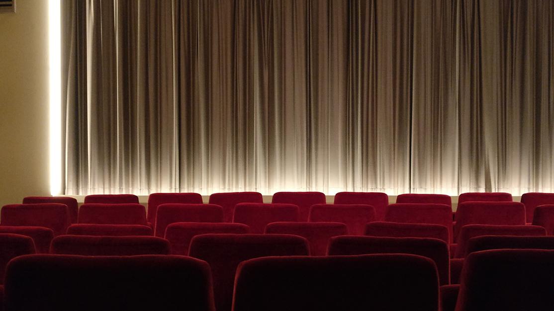 Theater with red chairs and curtain at front